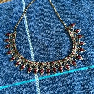 Gold antiqued chain and dark red stones make this statement piece a stunner